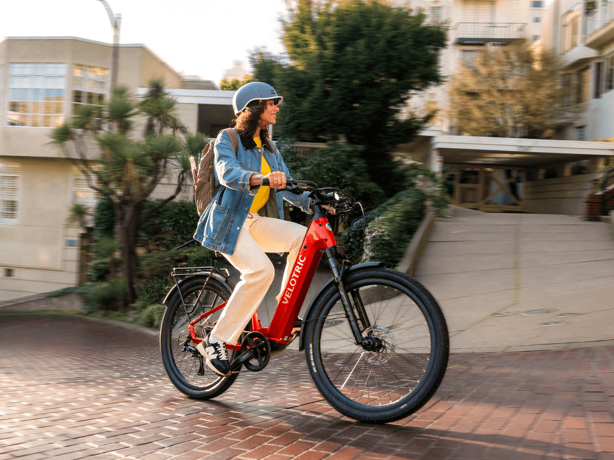 Rider on a Velotric Discover 3 in Cherry Crimson on a brick city street (Velotric photo) — Zeus eBikes Canada