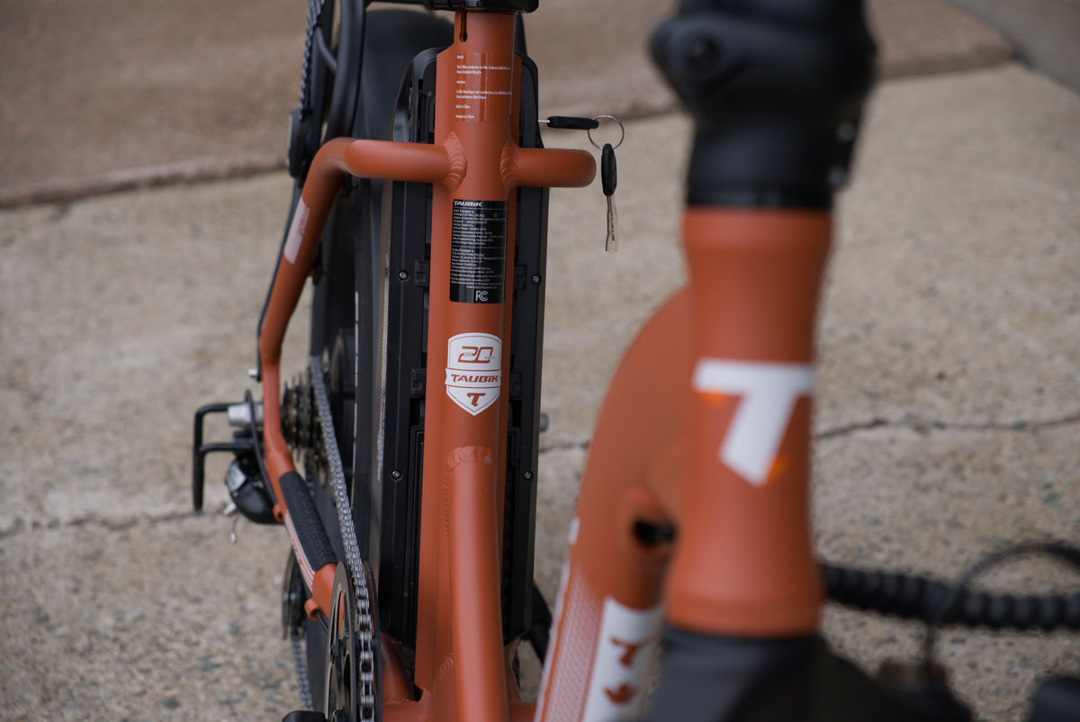 Taubik Escape S in Matte Clay Red: the battery behind the seat tube with its key, and the Taubik logo on the frame