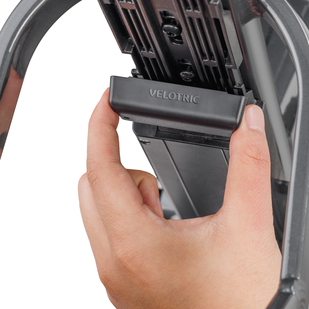 A hand fitting the Velotric battery connector cover onto the battery rail of a Velotric eBike