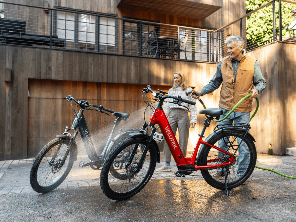 Two riders with Velotric Discover 3 e-bikes outside a house (Velotric photo) — Zeus eBikes Canada