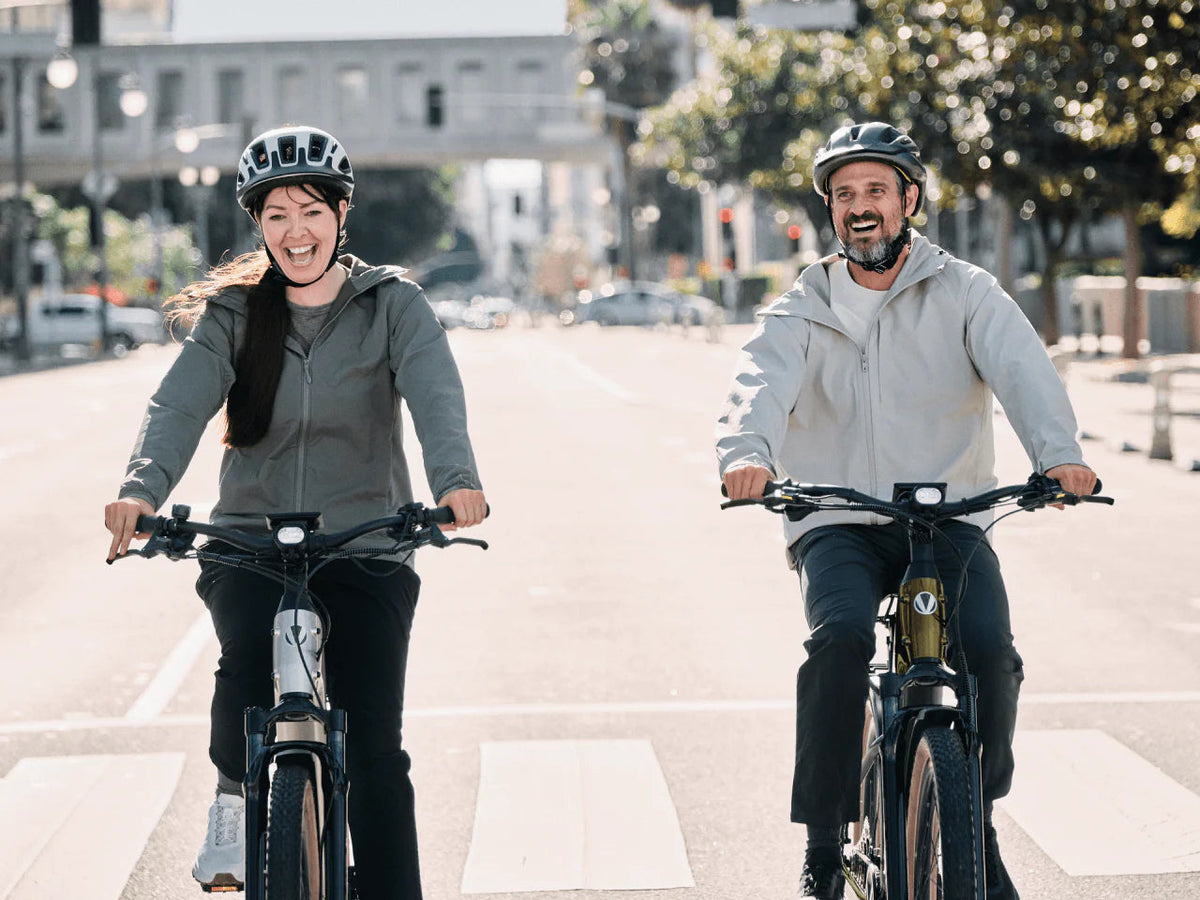 Two riders on Velotric Discover M e-bikes on a city street (Velotric photo) — Zeus eBikes Canada