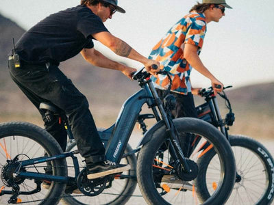 Two riders on blue-gray Freesky Warrior Ultra M-530 fat-tire eBikes on a dry lakebed at dusk — Zeus eBikes Canada