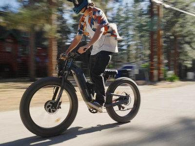 Rider standing on the pedals of a blue-gray Freesky Warrior Ultra M-530 at speed on a paved forest road — Zeus eBikes Canada