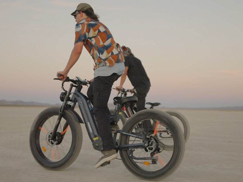 Two riders on Freesky Warrior Ultra M-530 fat-tire eBikes crossing open desert flats at sunset — Zeus eBikes Canada