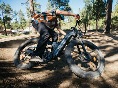 Rider cornering a blue-gray Freesky Warrior Ultra M-530 on a dirt pump track through pine forest — Zeus eBikes Canada