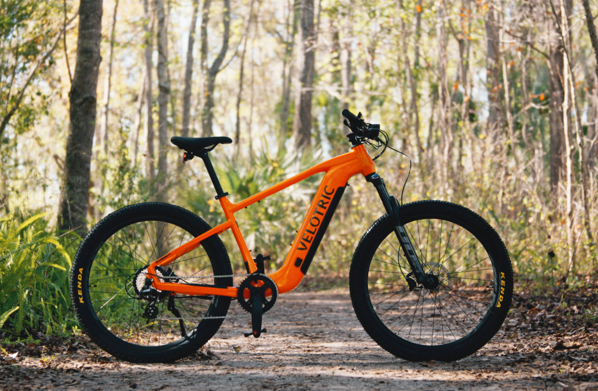 Velotric Summit 1 in Sunrise Orange parked in a forest (Velotric photo) — Zeus eBikes Canada