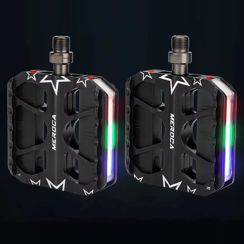 A left and right pair of MEROCA light-up pedals with red, green and blue light strips glowing against a dark background — Zeus eBikes Canada