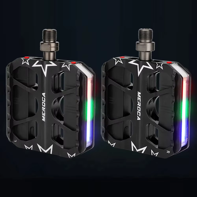 A left and right pair of MEROCA light-up pedals with red, green and blue light strips glowing against a dark background — Zeus eBikes Canada