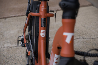 Taubik Escape S in Matte Clay Red: the battery behind the seat tube with its key, and the Taubik logo on the frame