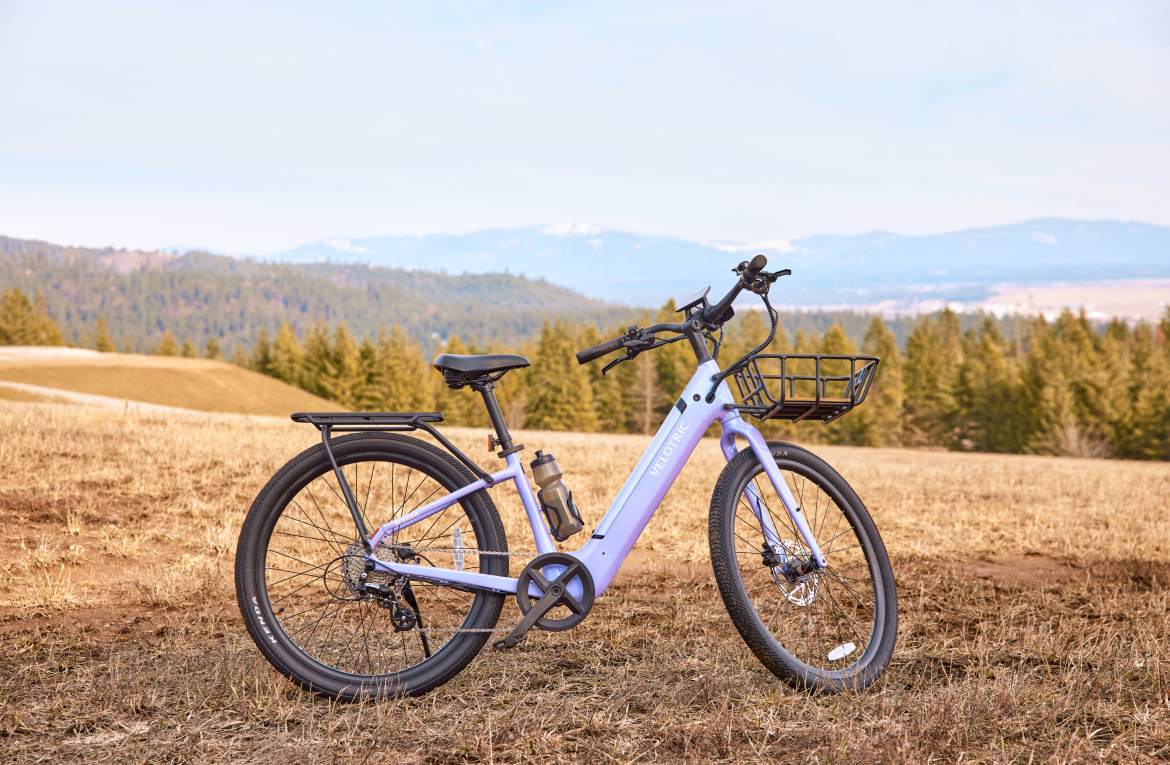 Velotric Breeze 1 in Violet Haze parked in a field, with the optional front basket, rear rack and bottle cage, sold separately (Velotric photo) — Zeus eBikes Canada
