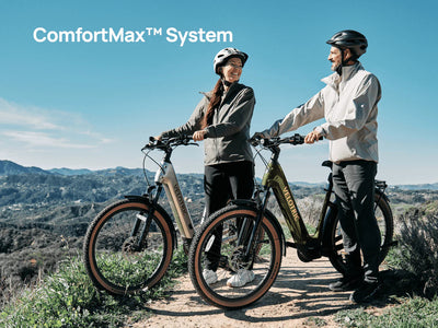 Two riders standing with Velotric Discover M e-bikes on a hilltop trail, with Velotric's ComfortMax caption — Zeus eBikes Canada