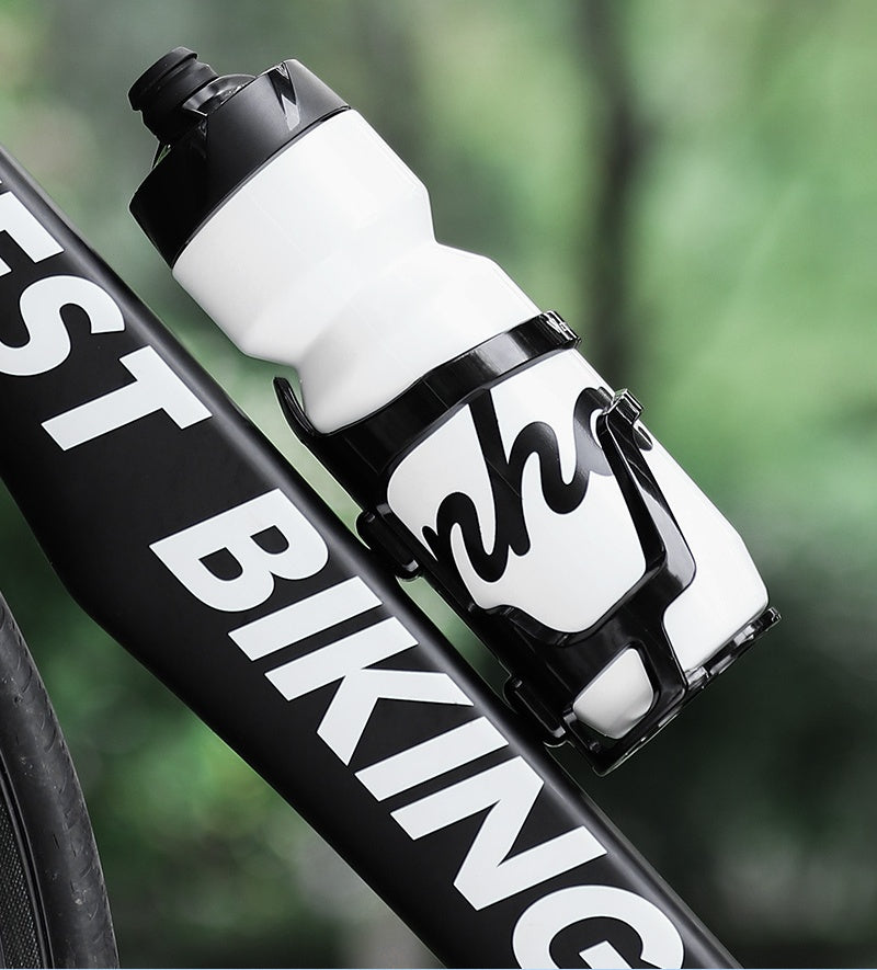 Black side-entry bike water bottle cage holding a white sport bottle on a bicycle down tube