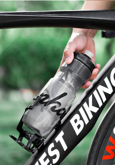 Rider pulling a water bottle sideways out of the cage mounted on a bike frame